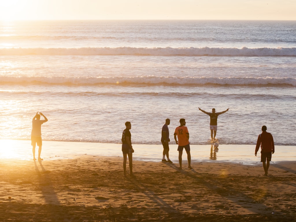 Een gemengde groep reizigers geniet samen van de zonsondergang op het strand